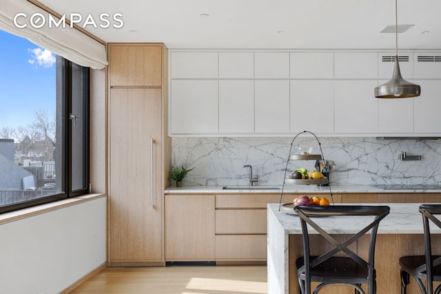 kitchen with a sink, light wood-style flooring, and modern cabinets