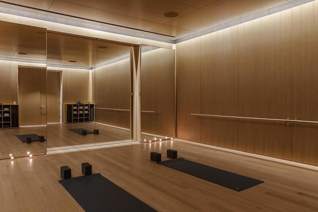 workout area featuring wood-type flooring and wooden walls