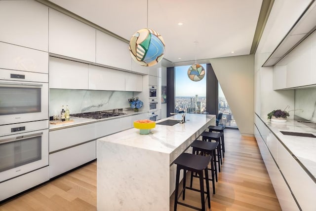 kitchen featuring white cabinetry, pendant lighting, and an island with sink