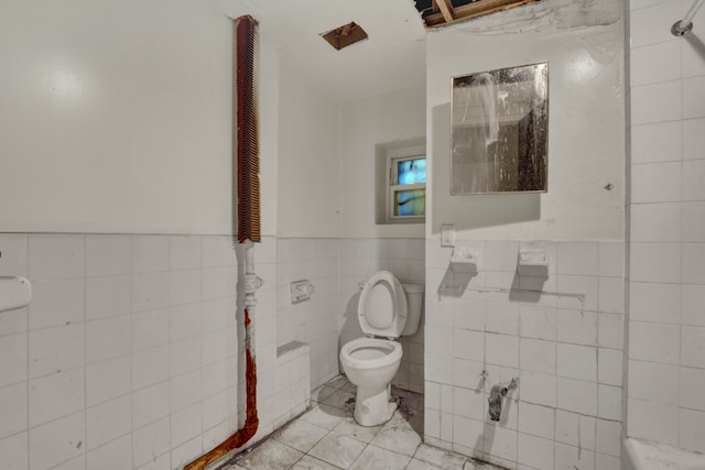 bathroom featuring toilet and tile walls