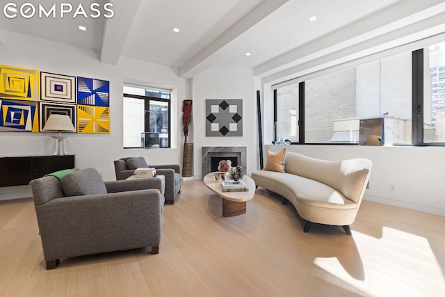 living room with light hardwood / wood-style floors, beam ceiling, and a premium fireplace