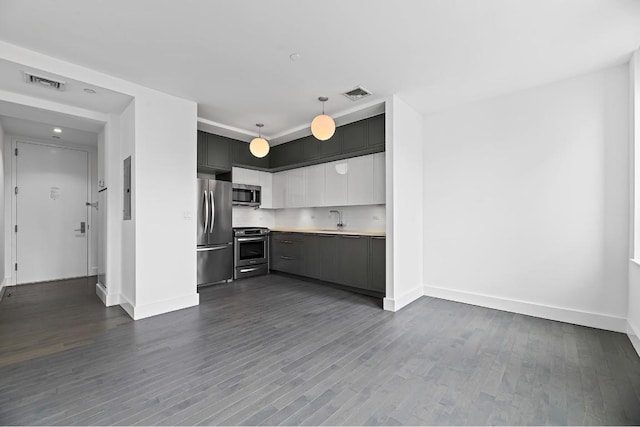 kitchen featuring sink, appliances with stainless steel finishes, white cabinetry, wood-type flooring, and decorative light fixtures