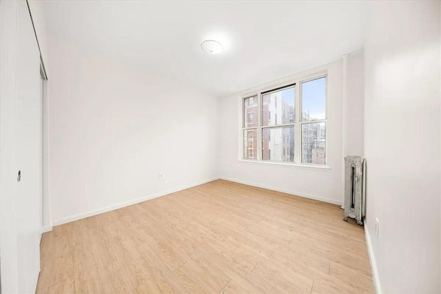 unfurnished room with radiator heating unit and light hardwood / wood-style flooring