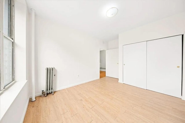 unfurnished bedroom with radiator, a closet, and light wood-type flooring