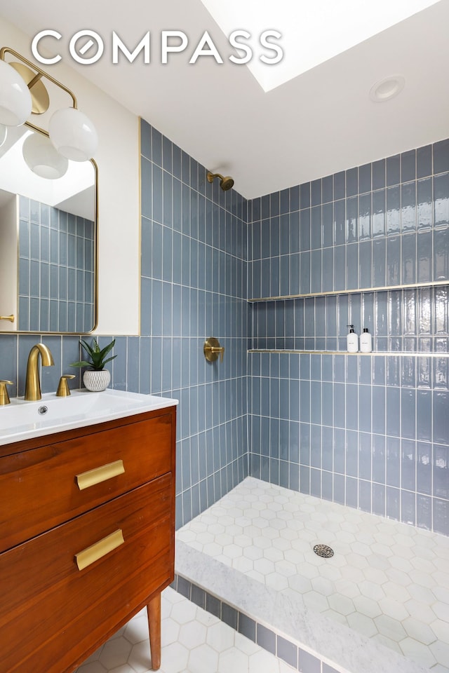 full bath featuring a tile shower, tile patterned floors, tile walls, and vanity