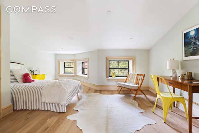 bedroom featuring multiple windows, light wood-type flooring, and baseboards