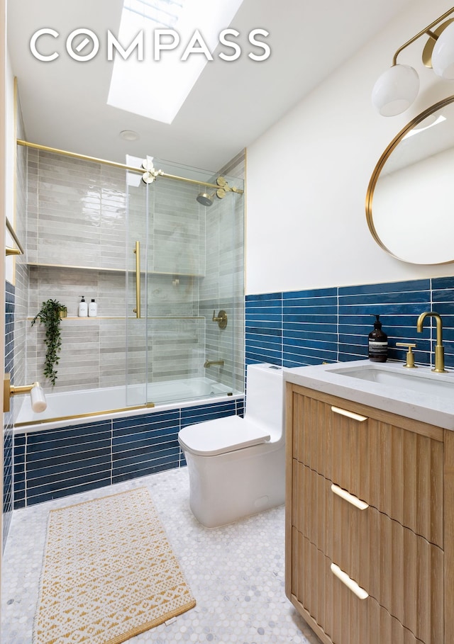 full bathroom featuring toilet, tiled shower / bath combo, tile walls, a skylight, and vanity