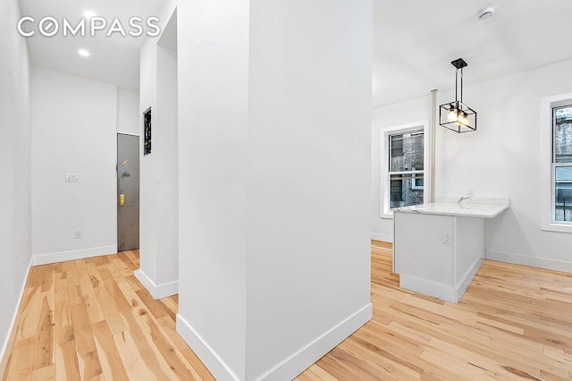 hall with light wood-type flooring and baseboards