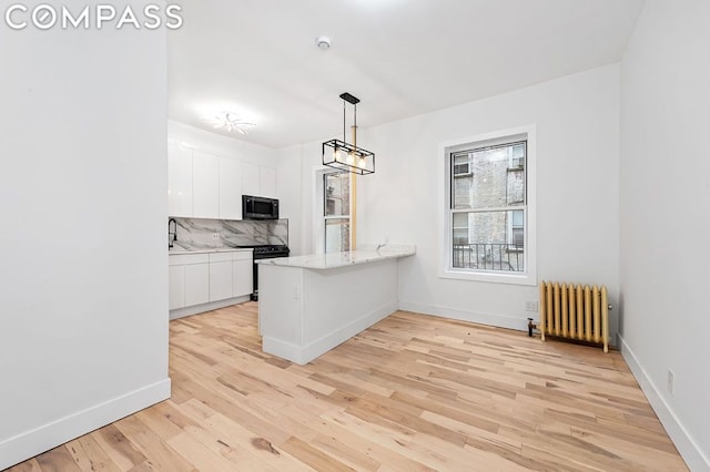 kitchen with electric range oven, kitchen peninsula, light hardwood / wood-style flooring, white cabinets, and radiator heating unit