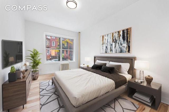 bedroom with light wood-type flooring, radiator heating unit, and baseboards