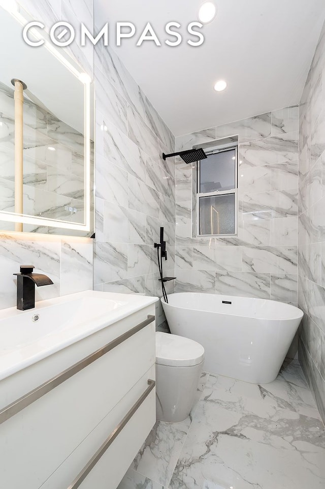 full bathroom with a freestanding bath, toilet, recessed lighting, stone wall, and vanity