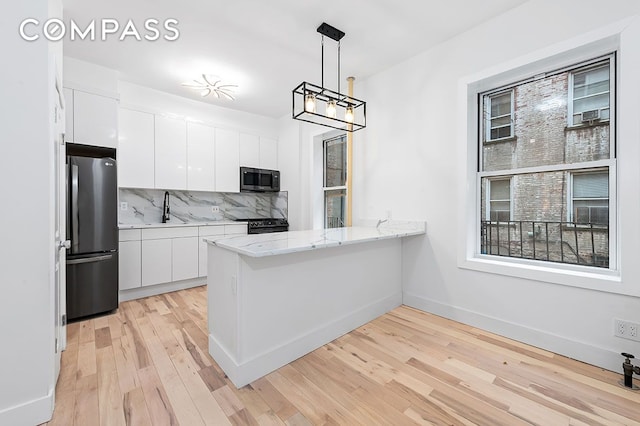 kitchen with decorative backsplash, light wood-style flooring, freestanding refrigerator, white cabinets, and a sink