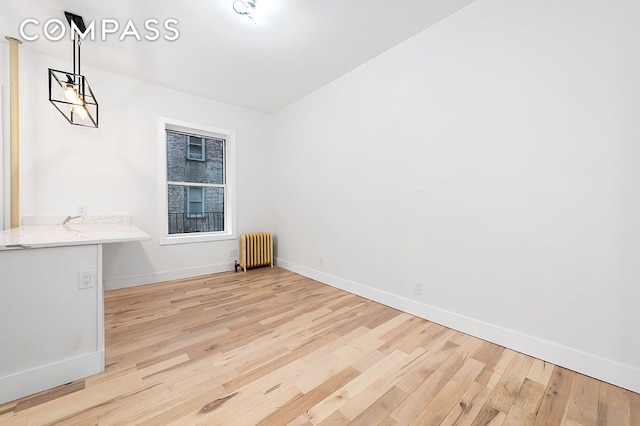 unfurnished dining area featuring radiator, baseboards, and light wood-type flooring