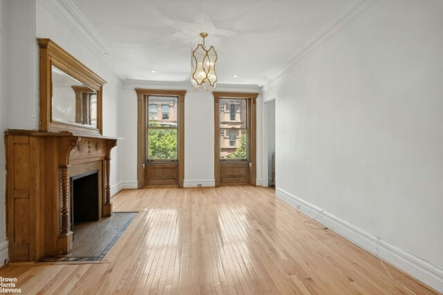 foyer featuring a premium fireplace, an inviting chandelier, parquet floors, and crown molding