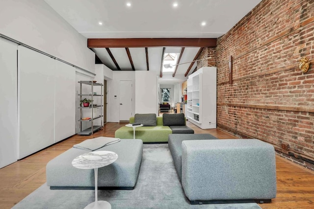 living room featuring light wood-style floors, lofted ceiling with skylight, and brick wall