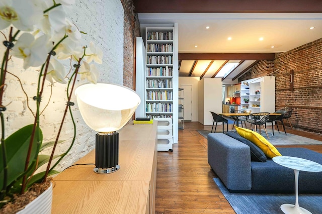 living room featuring wood finished floors, brick wall, and beamed ceiling