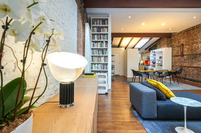 21 Bleecker St Unit 3-E, New York City, NY 10012 - living room with wood finished floors, beam ceiling, and brick wall