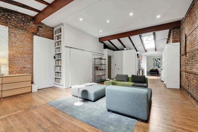 living area featuring lofted ceiling with beams, light wood-style floors, and brick wall