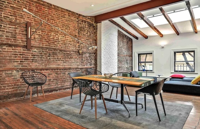 dining room with vaulted ceiling with skylight, wood finished floors, and brick wall