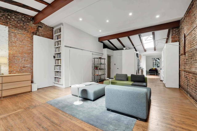 living room featuring brick wall, lofted ceiling with beams, and wood finished floors