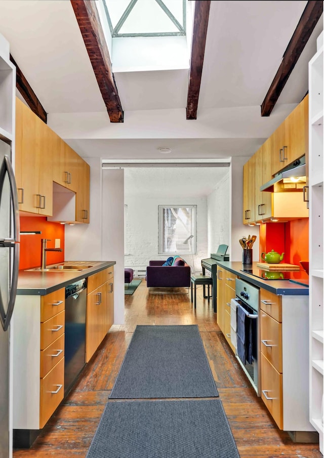 kitchen featuring dark wood-style flooring, appliances with stainless steel finishes, a sink, under cabinet range hood, and beamed ceiling