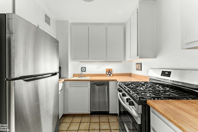 kitchen featuring stainless steel appliances, visible vents, butcher block counters, and a sink