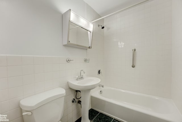 bathroom with tile walls, tile patterned flooring, tiled shower / bath combo, and toilet