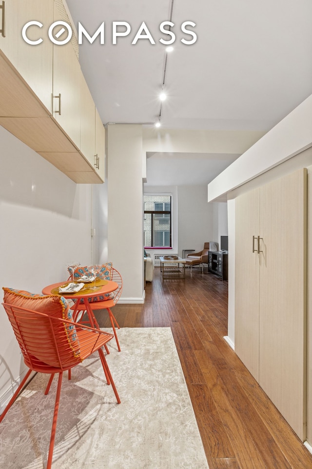 dining room featuring track lighting, baseboards, and hardwood / wood-style flooring