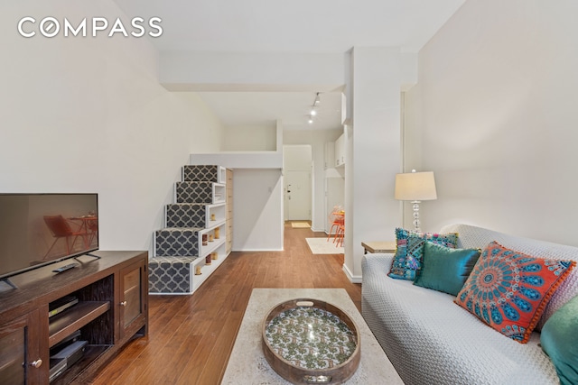 living area with baseboards, stairway, and wood finished floors