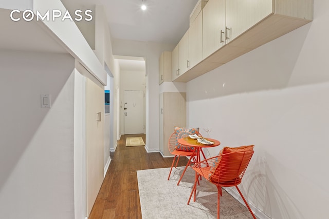 hall featuring dark wood-style flooring and baseboards