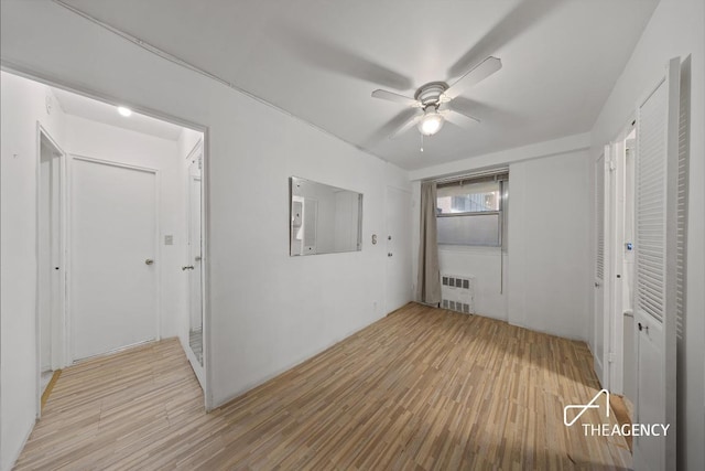 unfurnished bedroom with radiator heating unit, light hardwood / wood-style floors, and ceiling fan