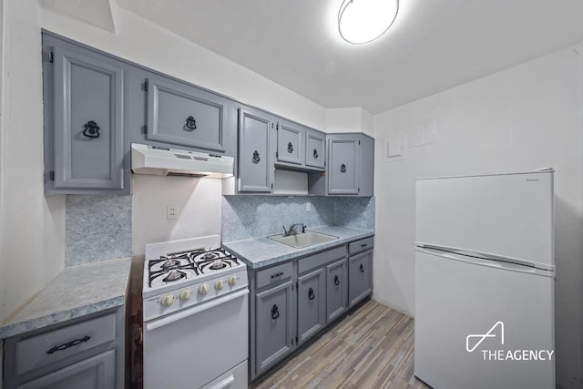 kitchen featuring sink, gray cabinetry, backsplash, and white appliances