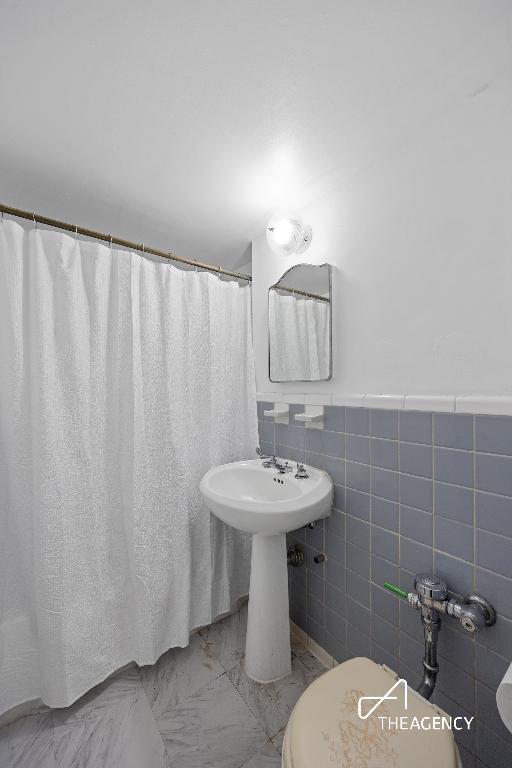 bathroom with tile walls and toilet