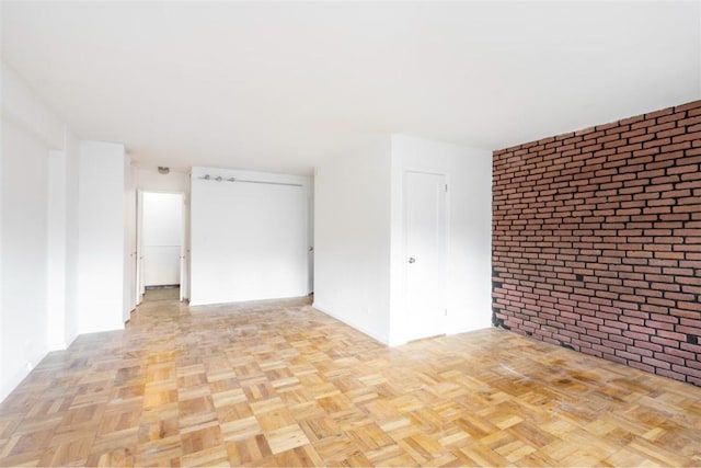 spare room with light parquet floors and brick wall