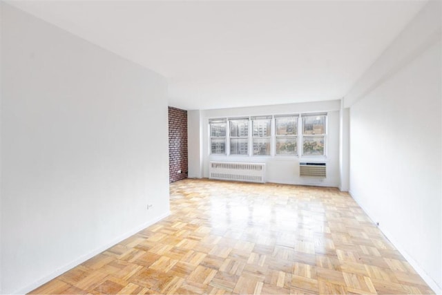 unfurnished living room featuring radiator heating unit, a wall unit AC, and light parquet flooring