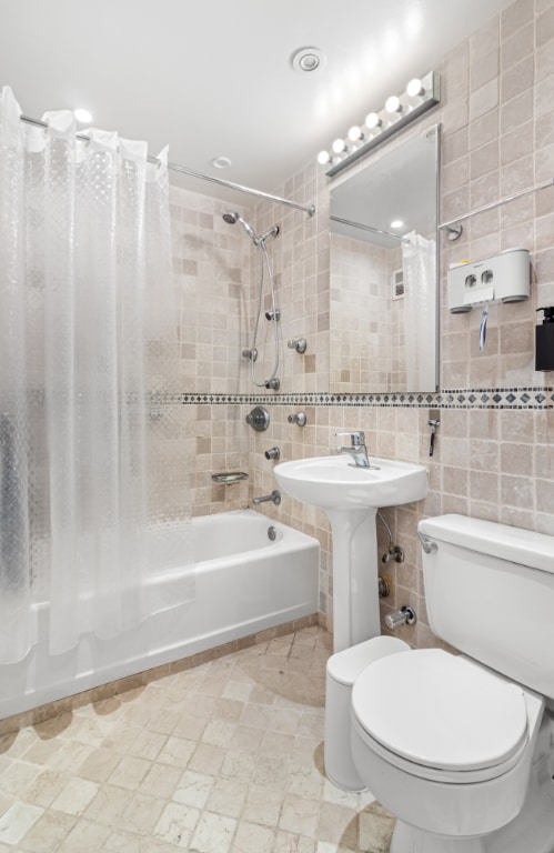 bathroom featuring toilet, tile walls, and shower / bathtub combination with curtain