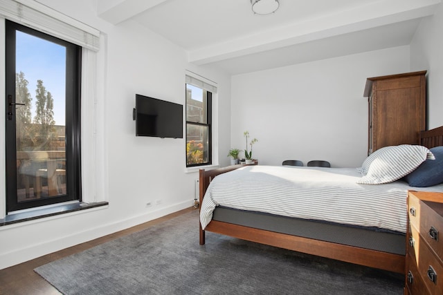 bedroom featuring beamed ceiling, wood finished floors, and baseboards