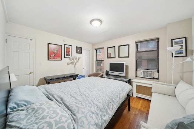 bedroom with cooling unit, hardwood / wood-style flooring, and radiator heating unit