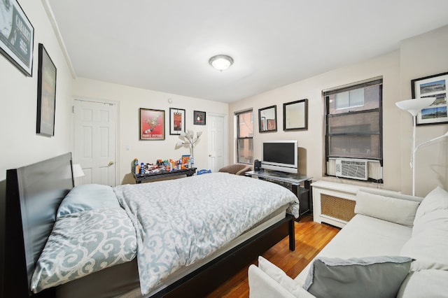 bedroom with cooling unit, wood-type flooring, and radiator