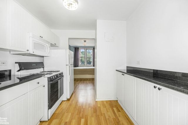 kitchen featuring white appliances, light wood finished floors, white cabinets, and dark stone countertops