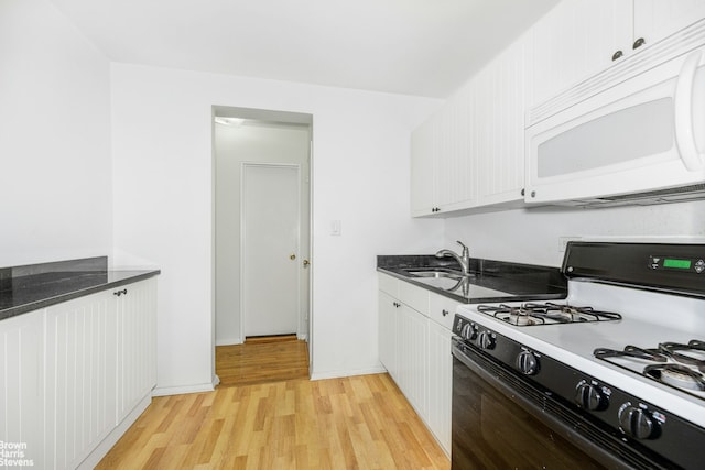 kitchen with gas range, white microwave, a sink, light wood finished floors, and white cabinets