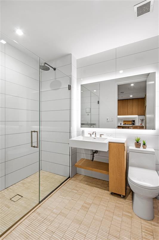 bathroom with visible vents, a tile shower, vanity, and toilet