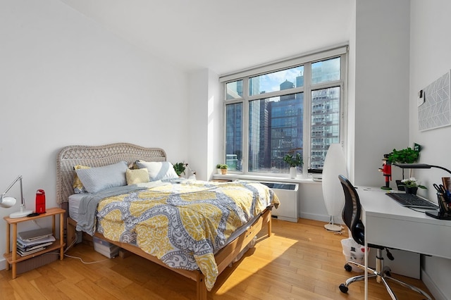 bedroom with light hardwood / wood-style floors and radiator heating unit