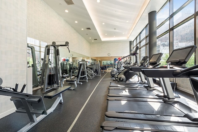 gym with a high ceiling and a tray ceiling