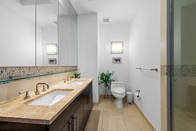 bathroom featuring toilet, decorative backsplash, tile patterned floors, an enclosed shower, and vanity