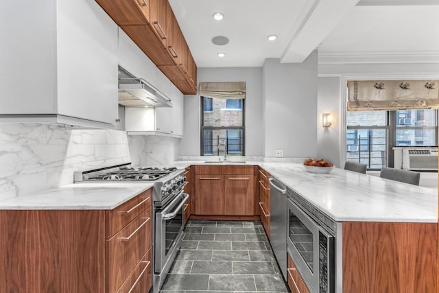 kitchen with kitchen peninsula, stainless steel appliances, decorative backsplash, a wealth of natural light, and sink