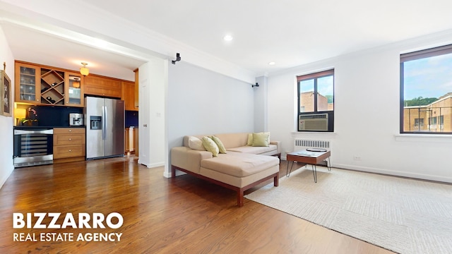 living room featuring a bar, radiator heating unit, beverage cooler, wood finished floors, and recessed lighting