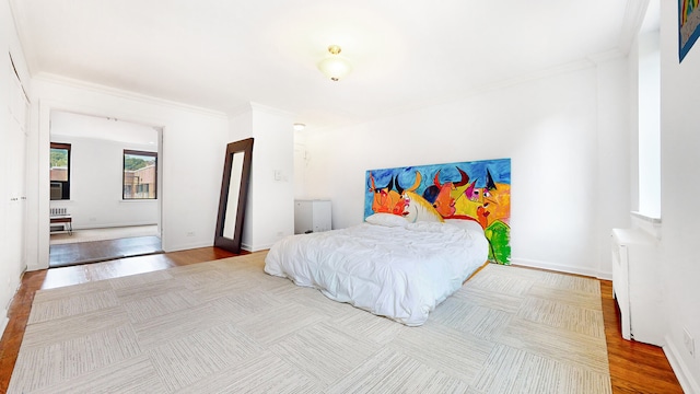 bedroom featuring radiator, ornamental molding, baseboards, and wood finished floors