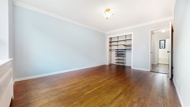 spare room with radiator heating unit, dark wood-type flooring, ornamental molding, and baseboards