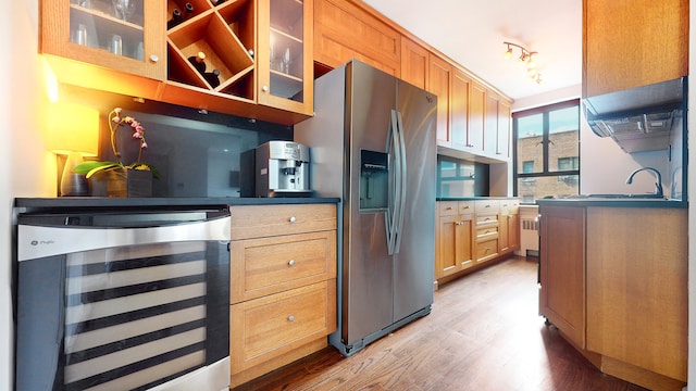 kitchen featuring wine cooler, stainless steel fridge with ice dispenser, light wood-type flooring, glass insert cabinets, and radiator
